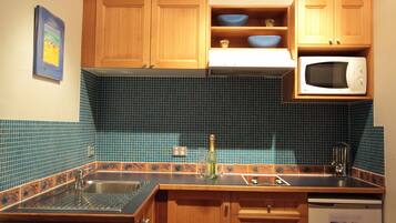 A kitchen with wooden cabinets, a microwave, a sink, and a tiled backsplash.