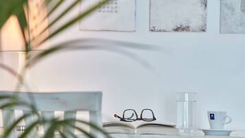 A wooden table with a book, glasses, a glass of water, and a cup on a white surface.