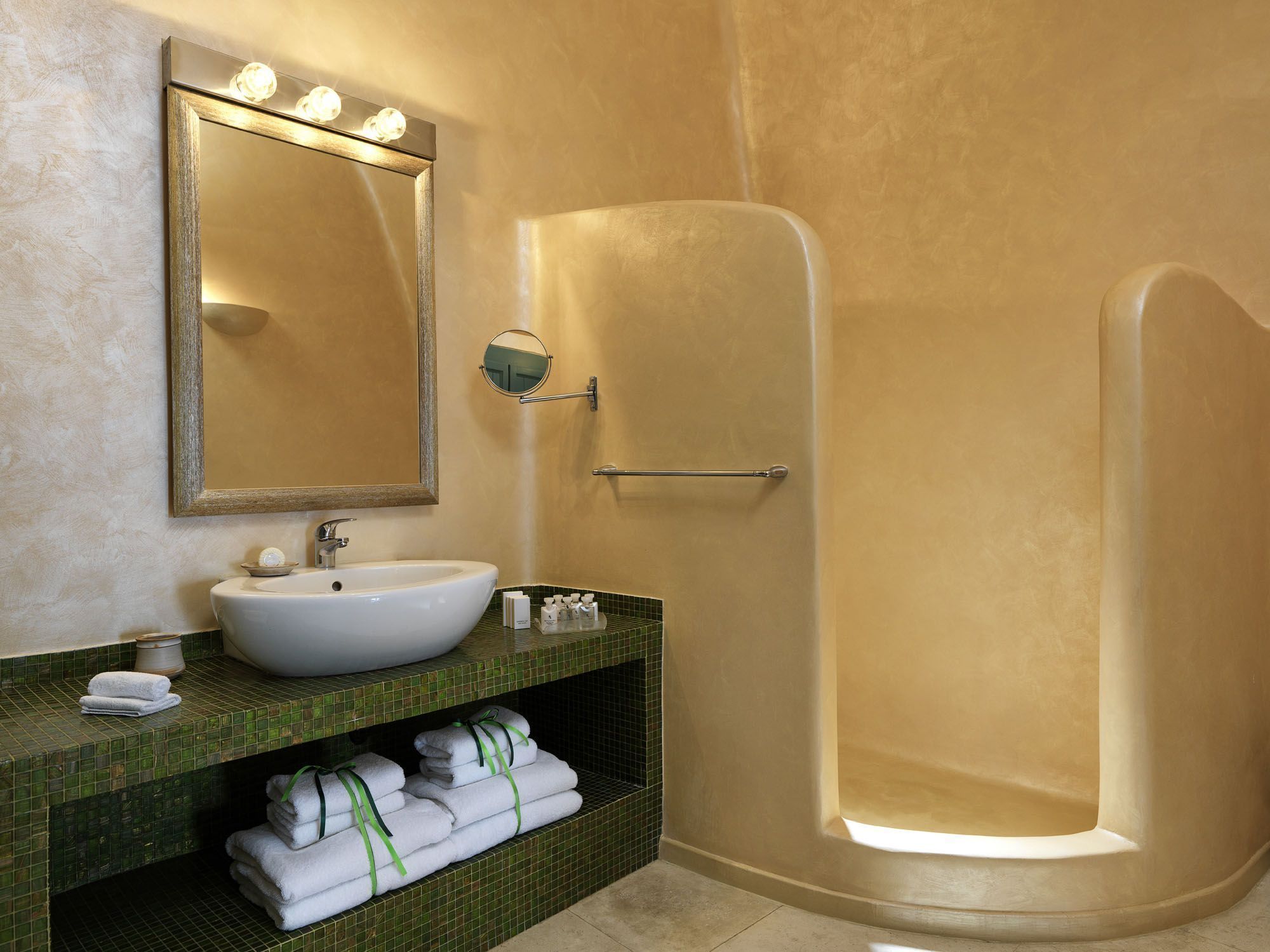 A bathroom with a large mirror, a sink, and a walk-in shower.