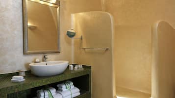A bathroom with a large mirror, a sink, and a walk-in shower.