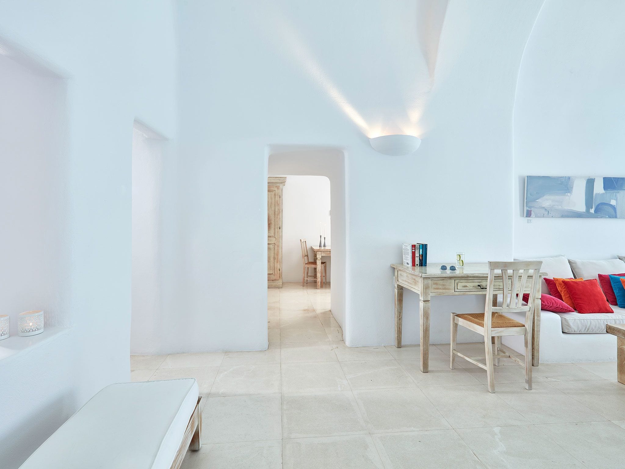 A minimalist living room with a white sofa, a wooden table, and a white bench.