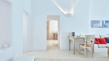 A minimalist living room with a white sofa, a wooden table, and a white bench.