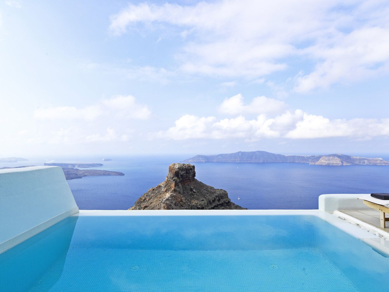 Piscina infinita com vista para uma ilha rochosa e o mar.