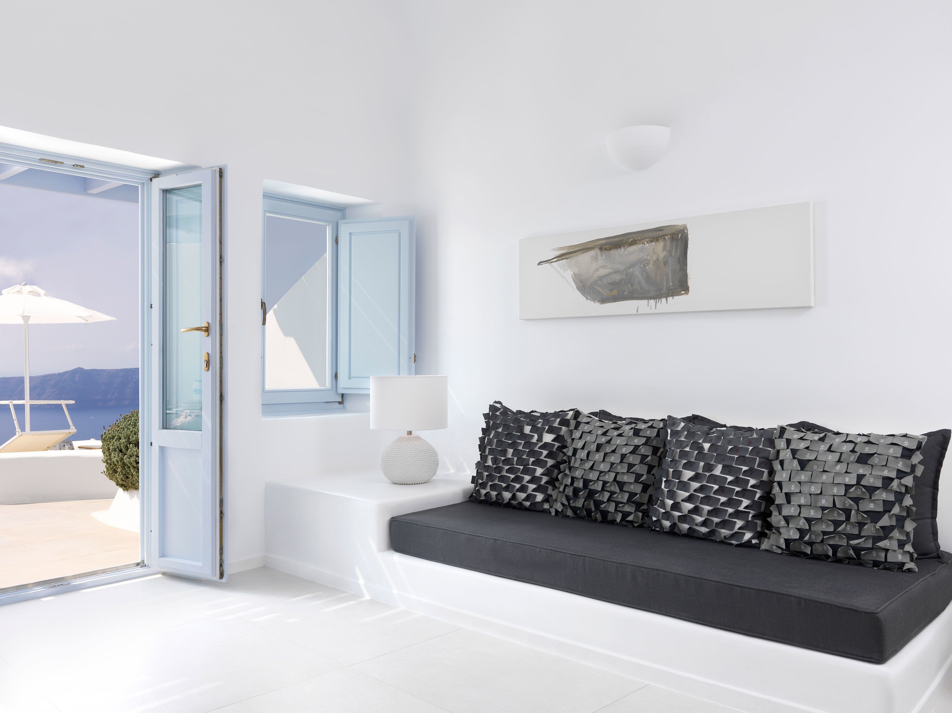 A modern living room with a white sofa, a lamp, and a painting on the wall.