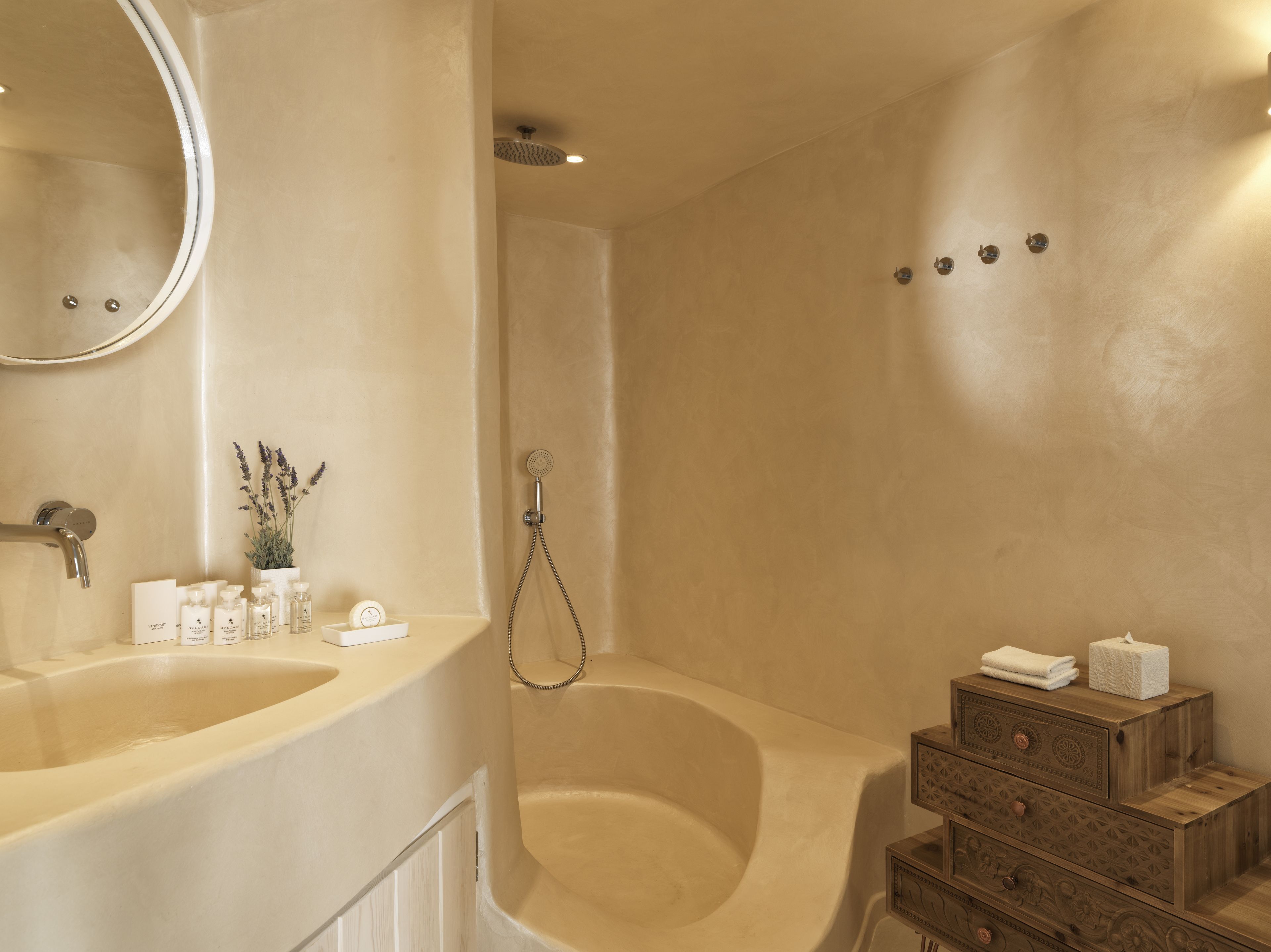 A bathroom with a bathtub, a sink, a mirror, and a wooden vanity with drawers.