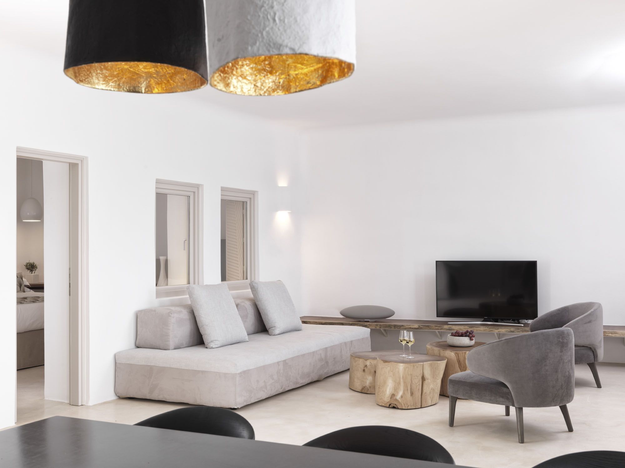 A modern living room with a sofa, chairs, a coffee table, and a TV.