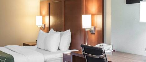 A hotel room with a bed, bedside lamps, a desk, and a chair.