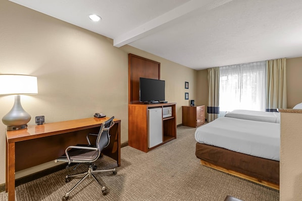 A hotel room with a desk, chair, television, minibar, and a bed. - Comfort Suites Airport (Boise)