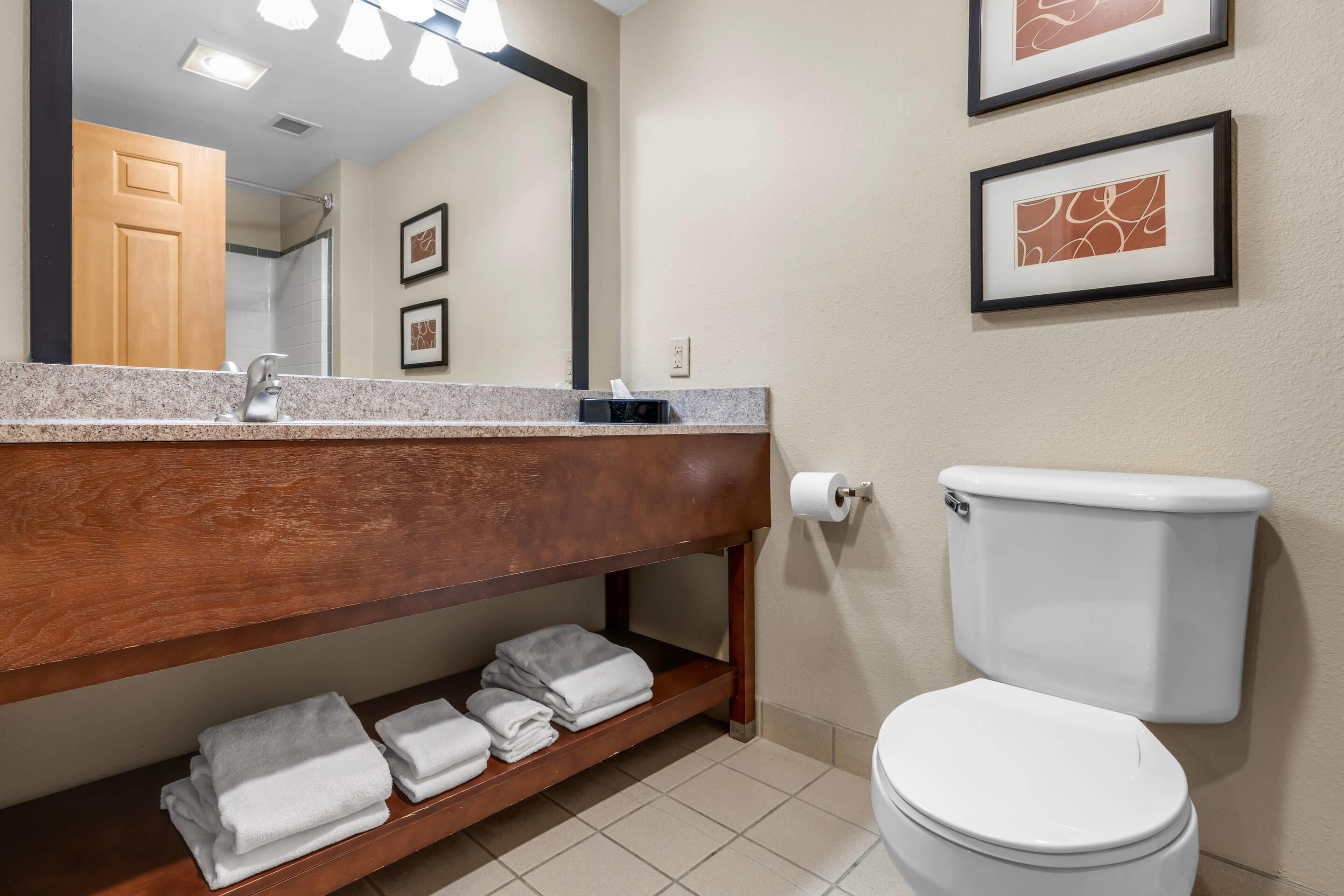 Ein Badezimmer mit Waschbecken, Spiegel, Toilette und Handtuchhalter.