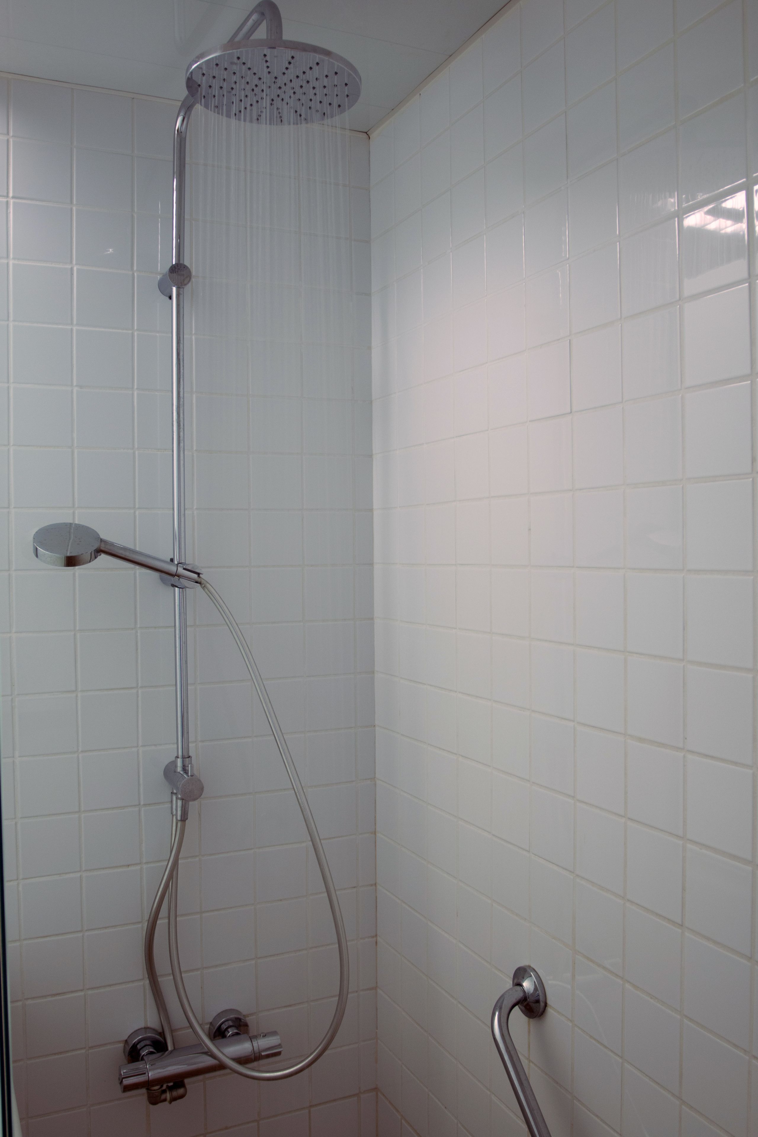 Ducha moderna con cabezal de ducha manual y manguera.