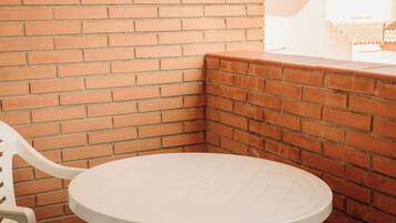 A corner of a room with a brick wall and a white table and chair.