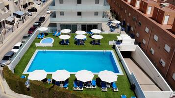 Una piscina al aire libre de temporada, sombrillas