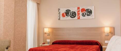 A hotel room with a bed, a sofa, a chair, and a wall-mounted artwork.