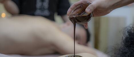 Una persona recibiendo un masaje con un líquido aplicándose en la espalda.