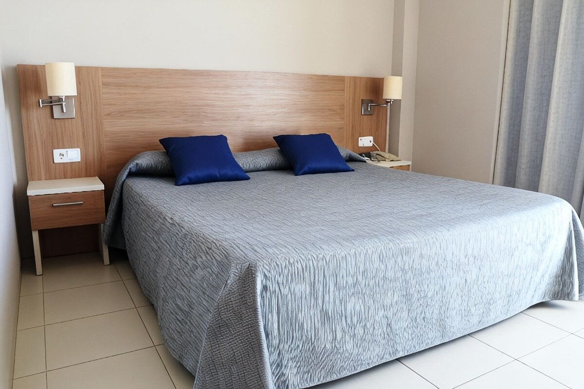 Une chambre d’hôtel avec un grand lit, deux tables de chevet et des lampes de chevet.