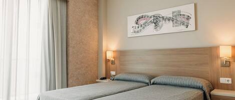 Habitación de hotel con dos camas, un ventanal con cortinas translúcidas, una obra de arte colgada en la pared y lámparas de noche.