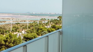 Un balcón con vistas despejadas de un paisaje costero, que incluye árboles y un horizonte urbano distante.