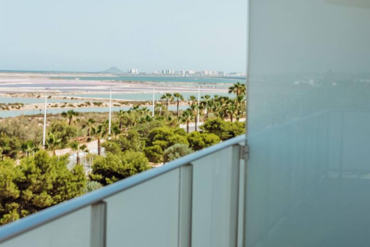 A balcony with a clear view of a coastal landscape, including trees and a distant cityscape.
