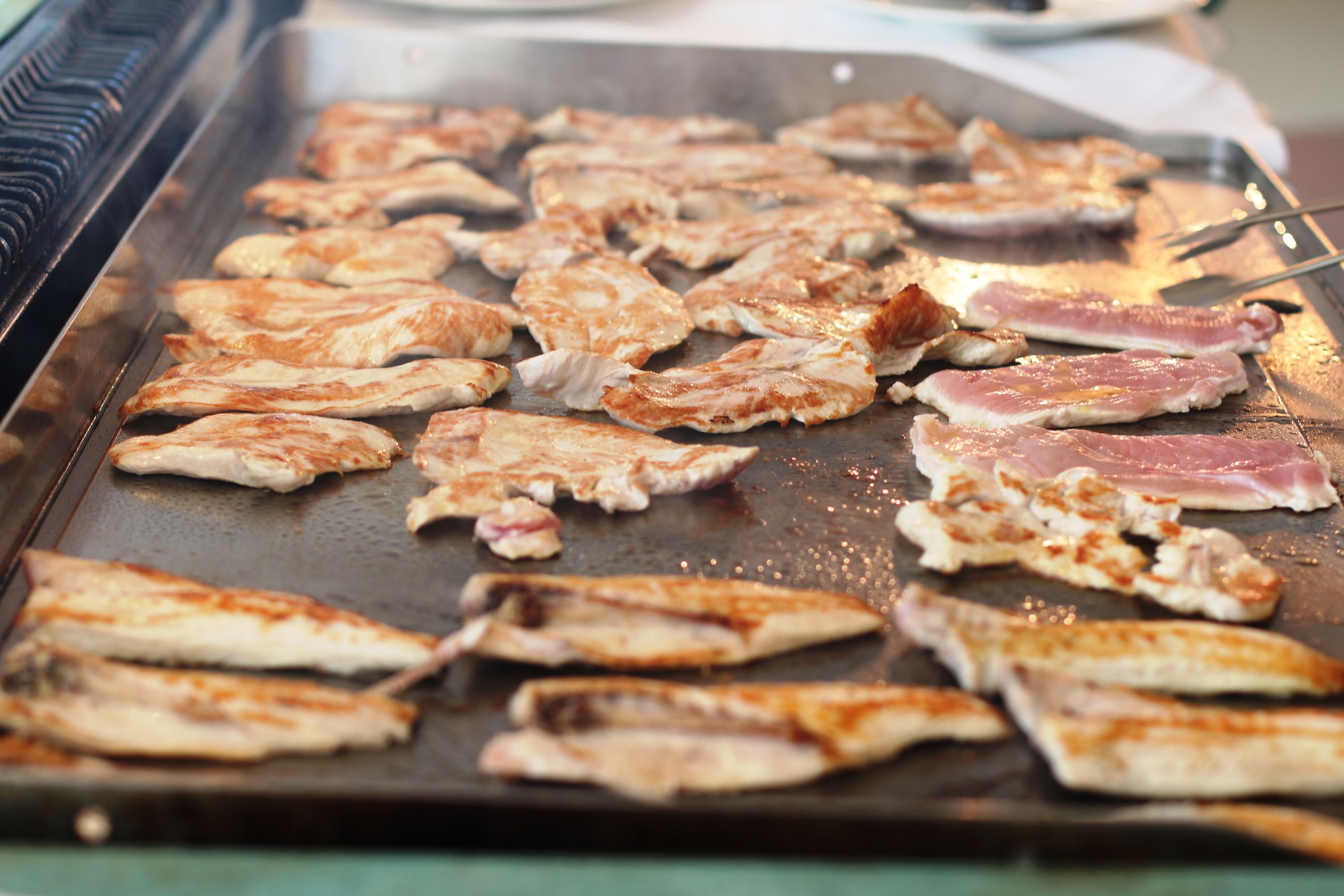 Una parrilla con diferentes cortes de carne asándose.