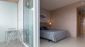 Un dormitorio con cama, mesita de noche, lámpara y ventana.
