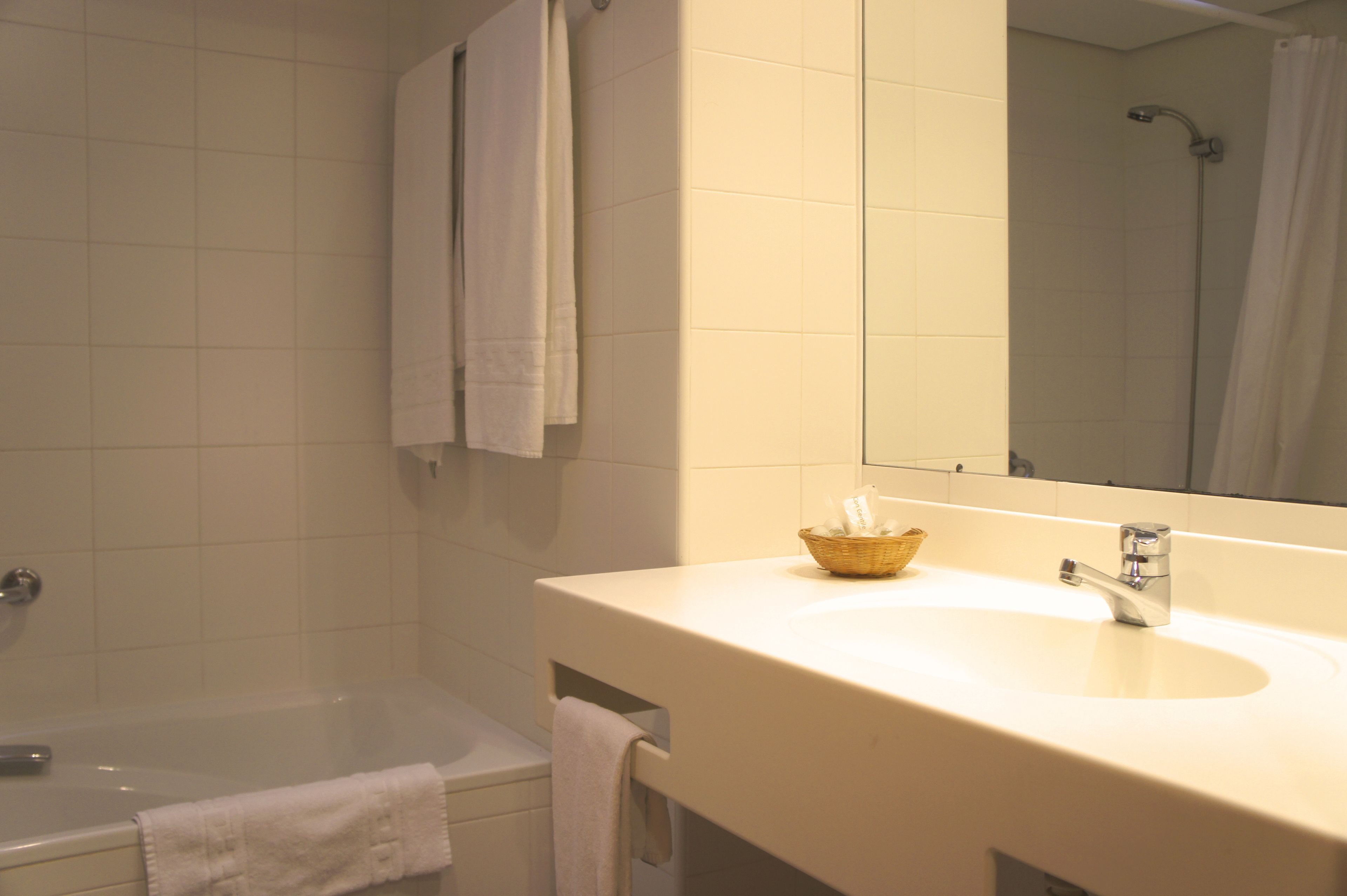 A bathroom with a bathtub, a sink with a mirror, and a shower area.