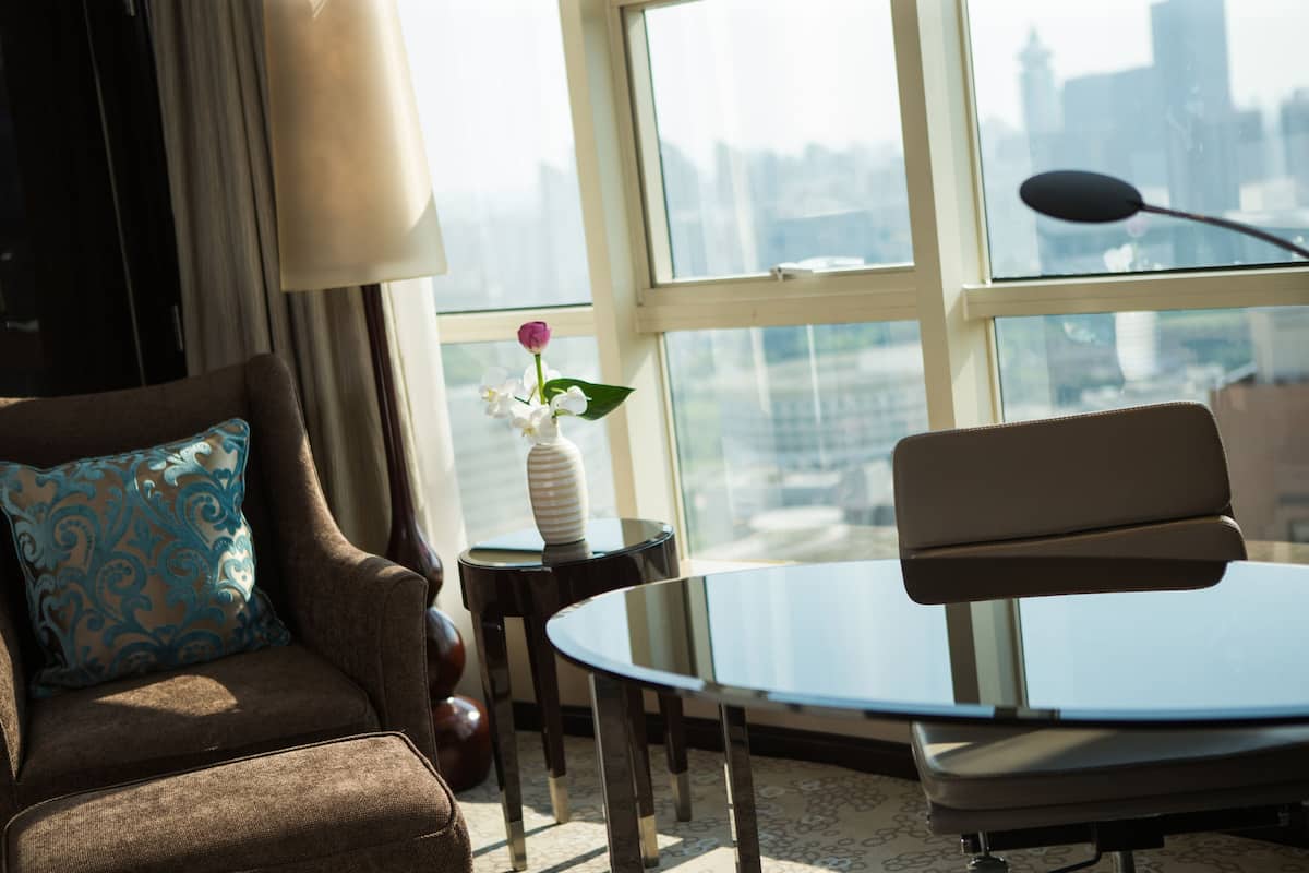 A modern living room with a sofa, a small round table, and a vase with flowers.