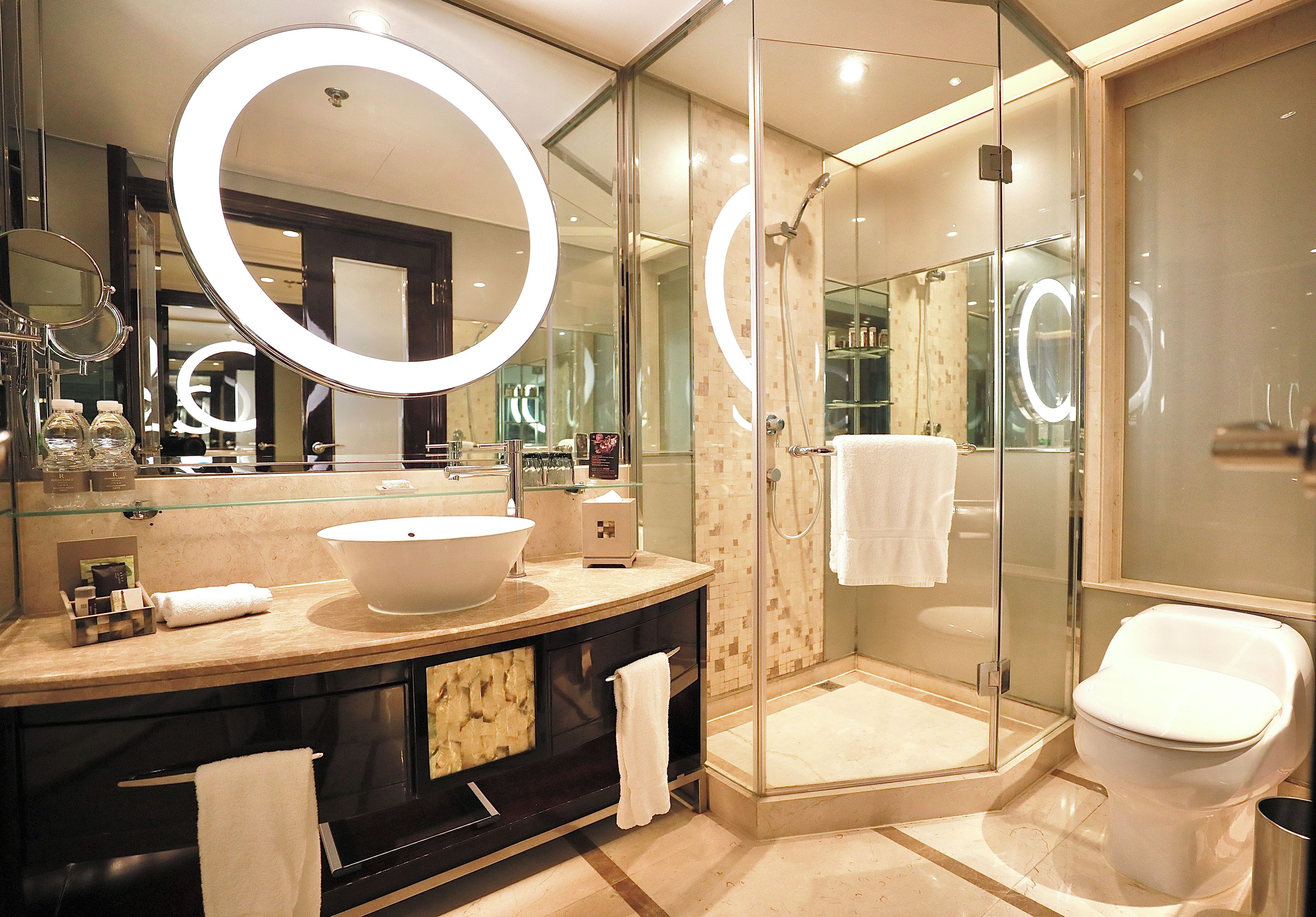 A modern bathroom with a large oval sink, a glass-enclosed shower, and a toilet.