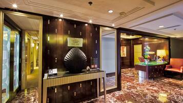 A hotel lobby with a reception desk, a lounge area, and a marble floor.