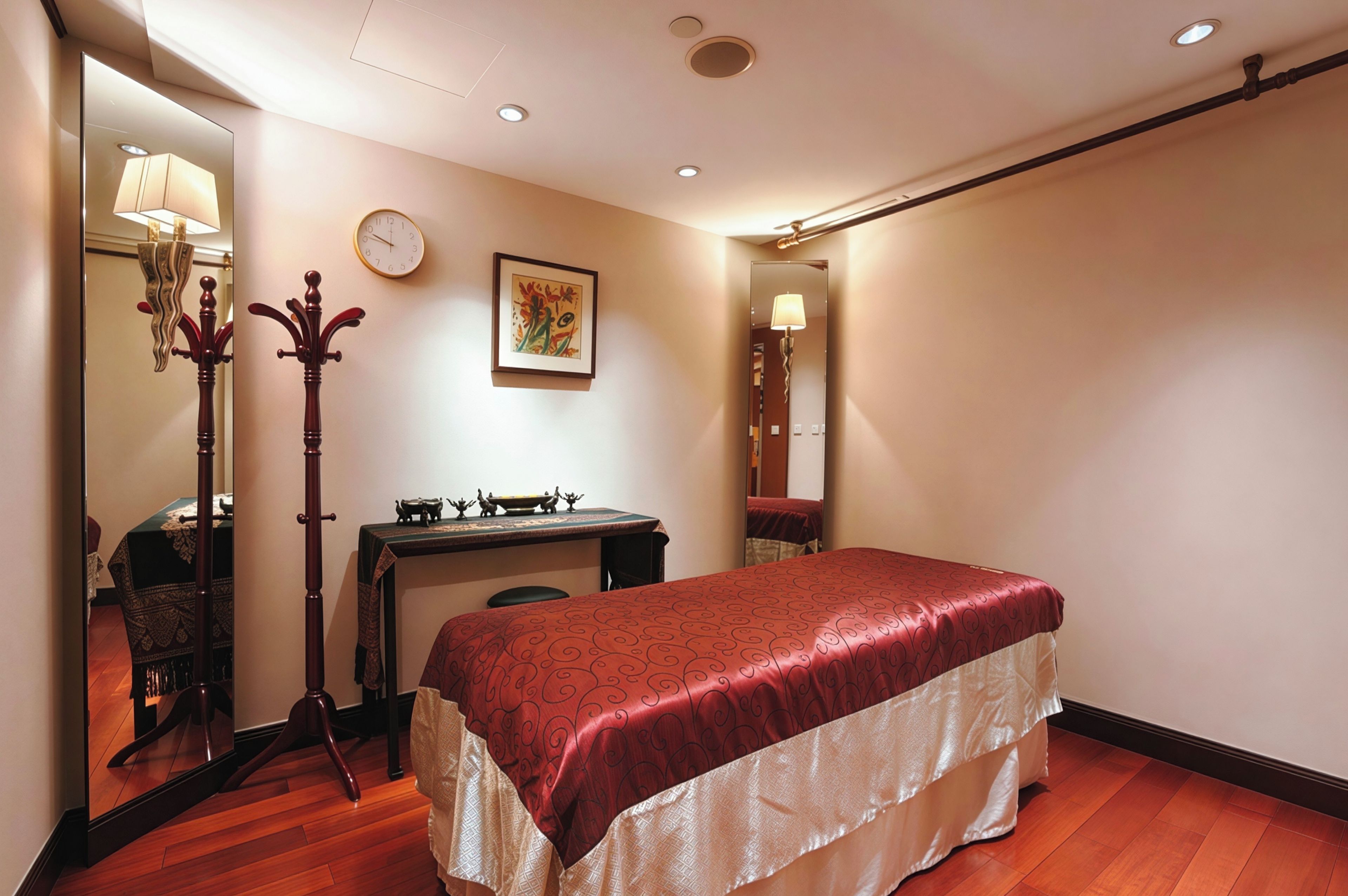 Habitación de hotel con cama, escritorio, silla, espejo, reloj y un adorno en la pared.
