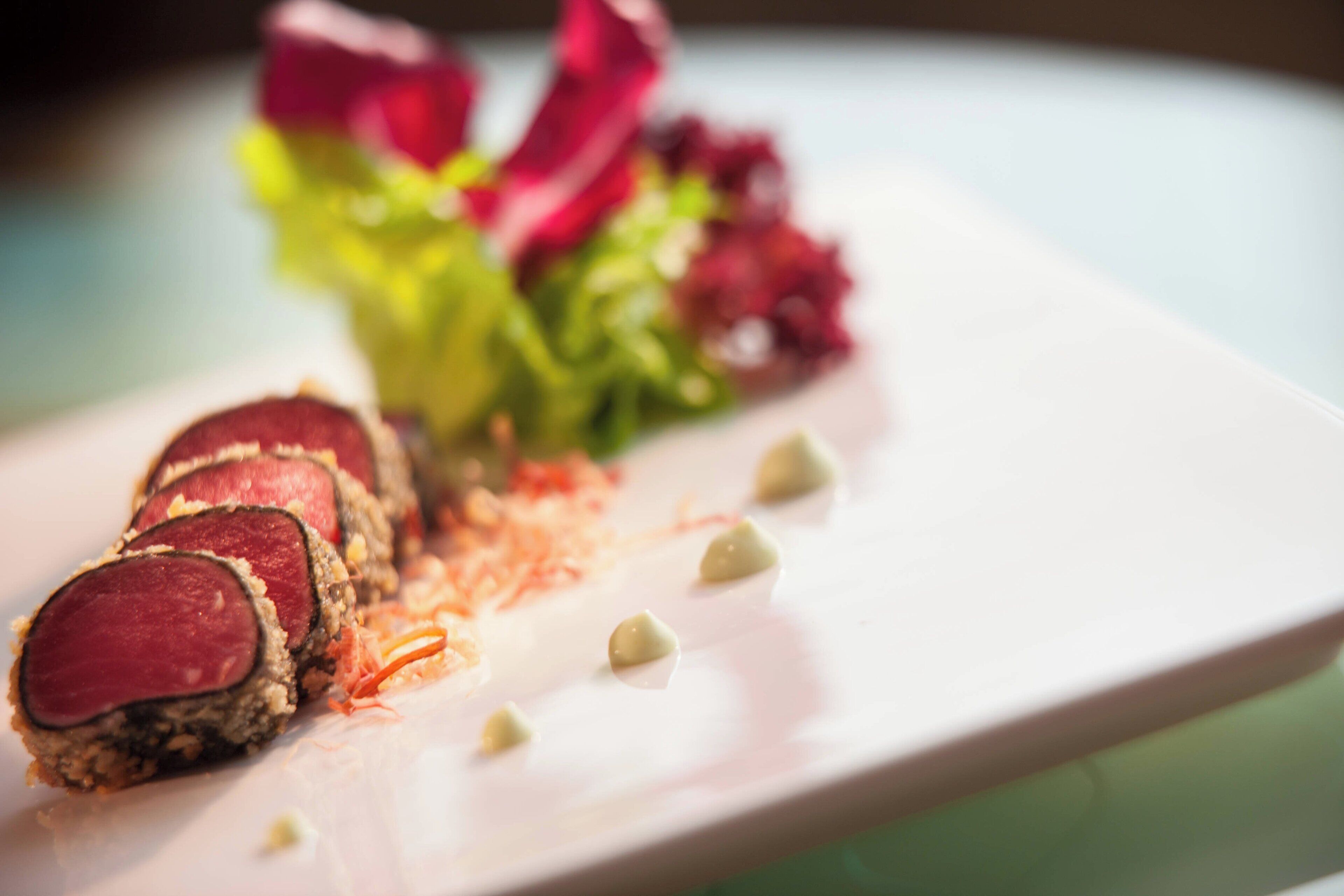 A plate with sliced meat, vegetables, and a sauce.