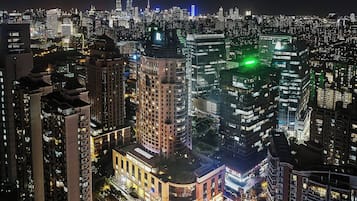 A nighttime cityscape with high-rise buildings, including a prominent building with a dome and a green-lit corner.