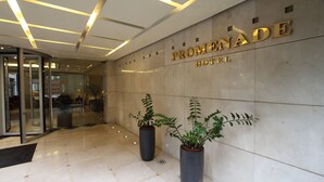 The Promenade Hotel entrance with a modern design, featuring a glass door, potted plants, and a marble floor. - PROMENADE HOTEL ZALKA (Zalqa)