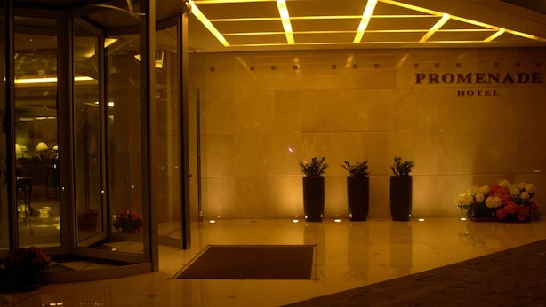 The entrance of the Promenade Hotel with a glass door, a tiled floor, and three potted plants. - PROMENADE HOTEL ZALKA (Zalqa)