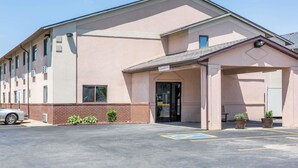 Un edificio con acceso cubierto, estacionamiento y un letrero con el nombre del establecimiento.
