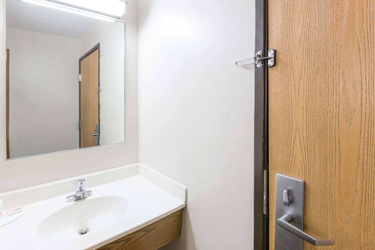 A bathroom with a white sink, a mirror, and a wooden door.
