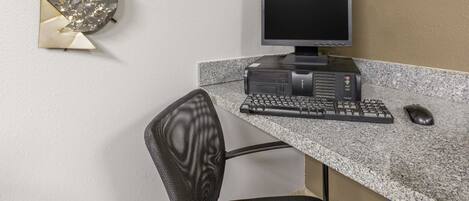 A computer desk with a monitor, keyboard, and mouse.