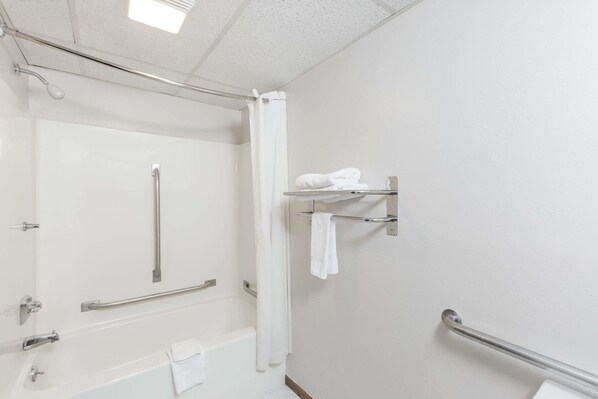 Une salle de bain équipée d’une douche, de barres d’appui, d’un porte-serviettes et de toilettes.