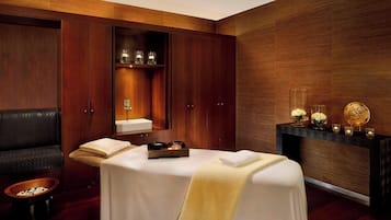 Relax in a serene spa room with a massage table, leather sofa, and candlelit table.