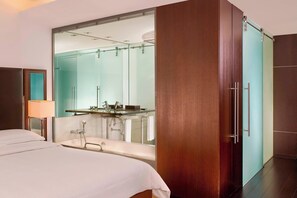 A modern hotel room with a large bed, a bathroom with a glass shower enclosure, and a wooden wardrobe. - Sheraton Porto Hotel & Spa (Porto)