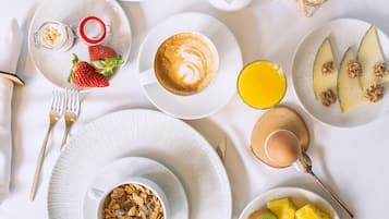 Desayuno con diversas comidas y bebidas sobre una mesa blanca.
