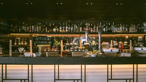 A bar area with a variety of bottles and glasses on shelves, a beer tap, and several decorative items including flowers and small vases.