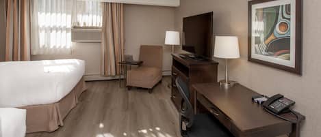 Una habitación de hotel con una cama, un escritorio con una silla, un televisor y un teléfono.