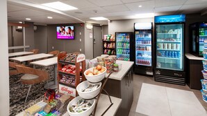 Zona de restauració amb seients, un taulell amb productes alimentaris i màquines expenedores.