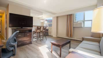 Una sala de estar moderna con televisor de pantalla plana, muebles de madera, un sofá y un comedor con sillas.