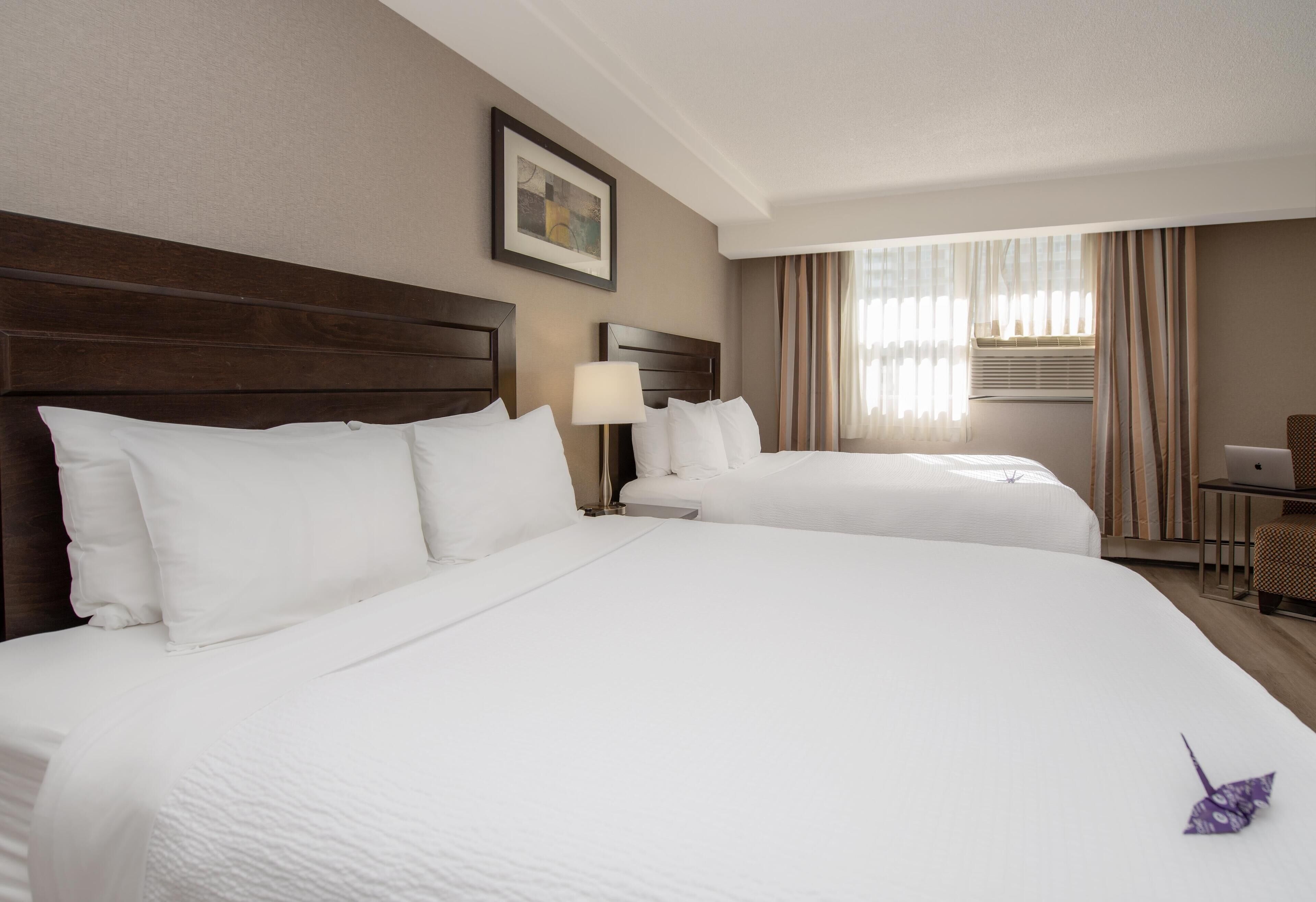 A hotel room with two beds, a desk, and a chair.