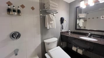 Un baño moderno con inodoro, lavamanos y bañera. Hay toallas y artículos de aseo en la pared.