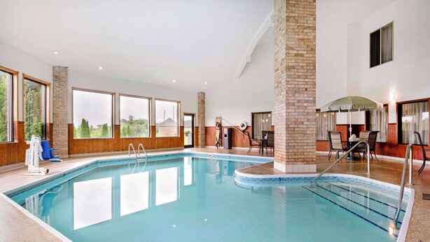 Una piscina interior con agua cristalina, rodeada de paredes de madera y amplias ventanas.