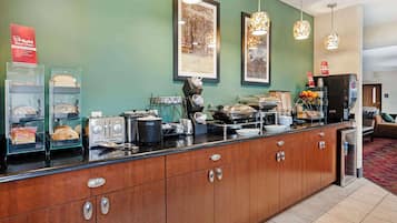 A hotel reception area with a wooden counter, a coffee machine, a toaster, and a refrigerator.