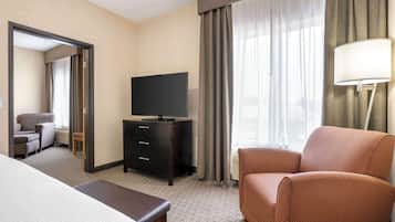 Ein Hotelzimmer mit Bett, Fernseher auf einer Kommode, Stuhl und Lampe.