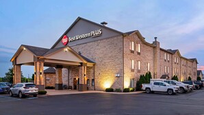 Un hotel Best Western PLUS con fachada de ladrillo, entrada cubierta y aparcamiento con varios vehículos.